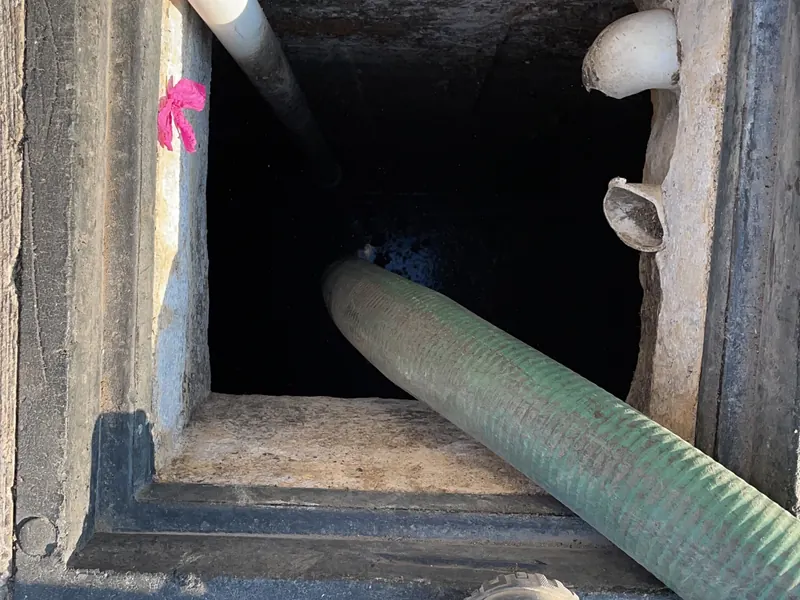 Técnico de Acuatec introduciendo manguera para desazolve de fosa séptica