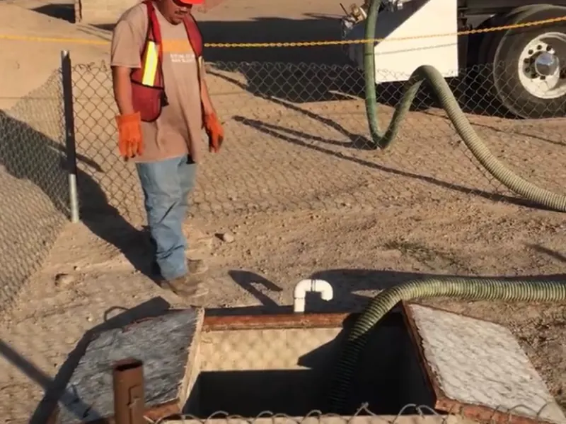 Técnico de Acuatec realizando succión de fosa séptica con equipo de seguridad